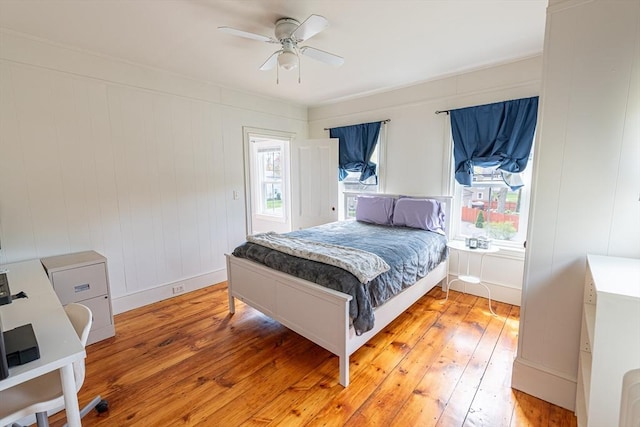 bedroom with light wood finished floors, multiple windows, ceiling fan, and baseboards