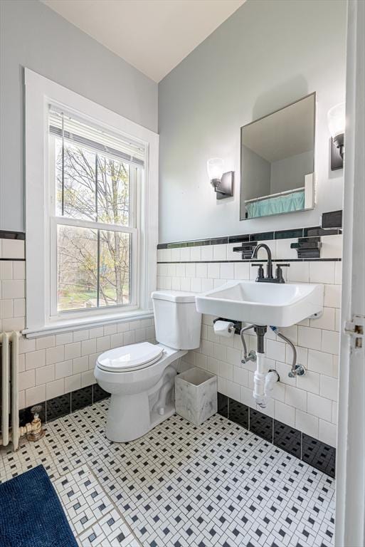 bathroom featuring radiator, toilet, tile walls, tile patterned floors, and wainscoting