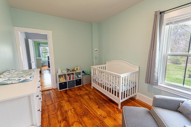 bedroom with a crib, hardwood / wood-style flooring, and multiple windows