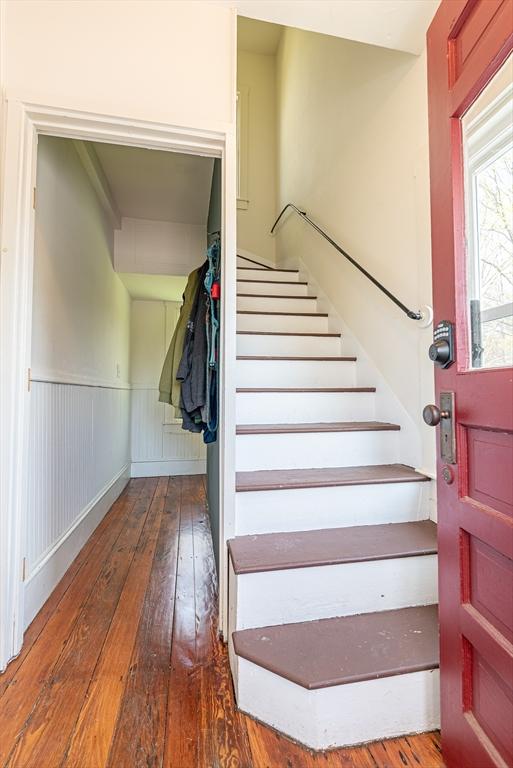 stairway with a wainscoted wall and hardwood / wood-style floors