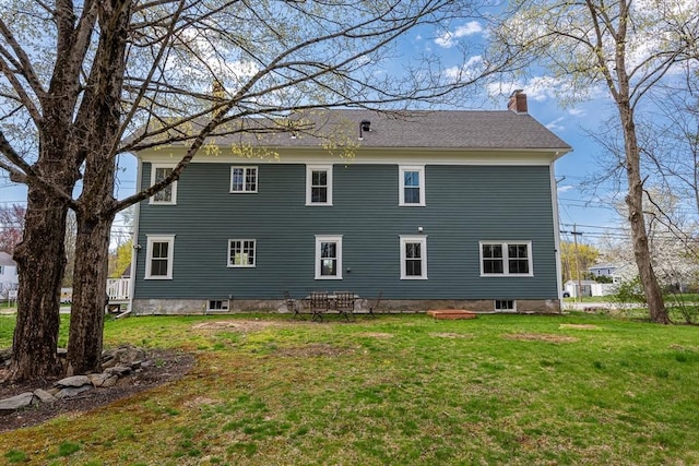 back of property featuring a chimney and a yard