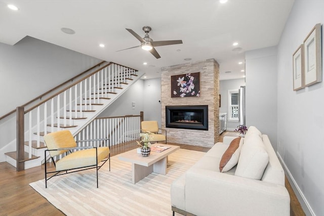 living room with ceiling fan, a fireplace, and light wood-type flooring