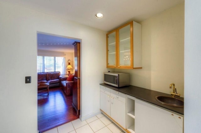 kitchen with white cabinetry, sink, and light wood-type flooring