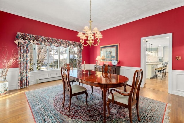 dining area with hardwood / wood-style flooring, a baseboard radiator, and a chandelier