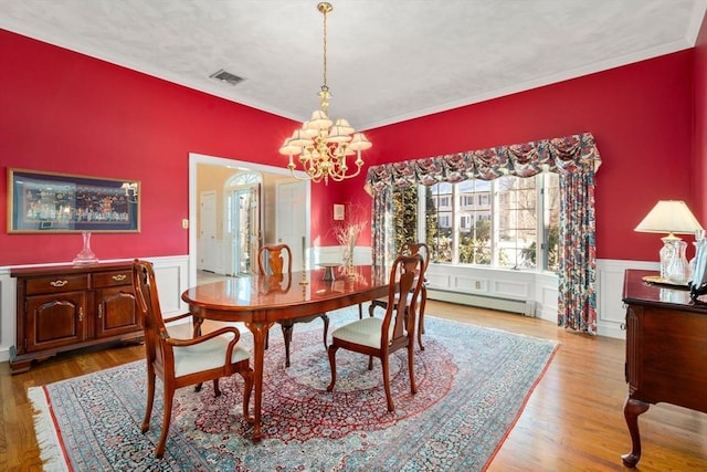 dining room with a chandelier, light hardwood / wood-style floors, a textured ceiling, and a baseboard heating unit