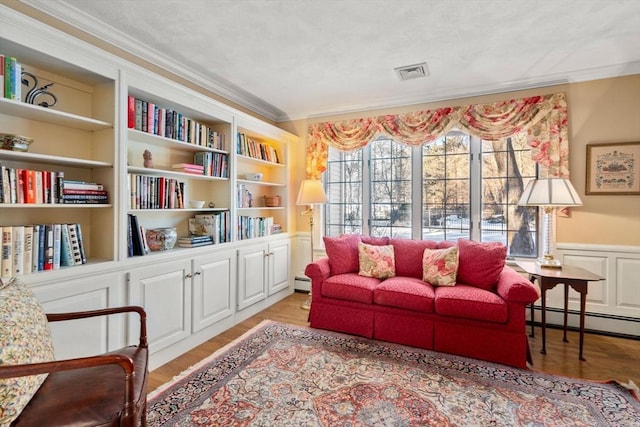 living area featuring crown molding, a baseboard heating unit, and light wood-type flooring