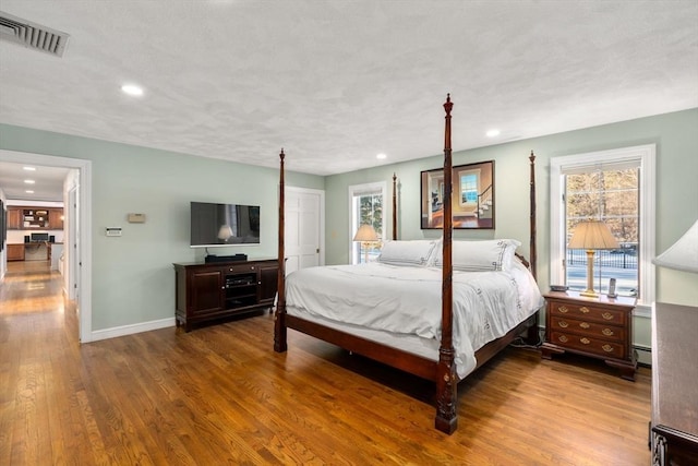 bedroom featuring wood-type flooring and a baseboard heating unit