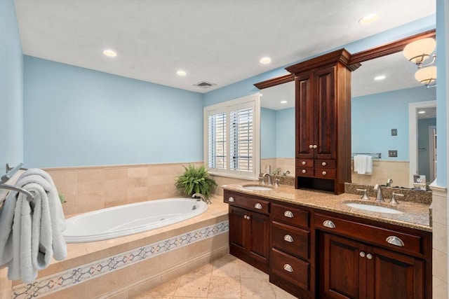 bathroom featuring vanity, a relaxing tiled tub, and tile patterned floors