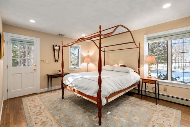 bedroom featuring wood-type flooring and a baseboard heating unit