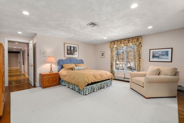 bedroom featuring baseboard heating and wood-type flooring