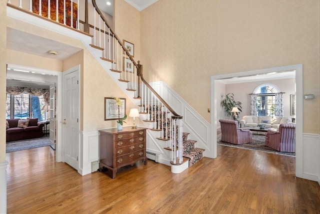 staircase featuring hardwood / wood-style flooring, a towering ceiling, and baseboard heating