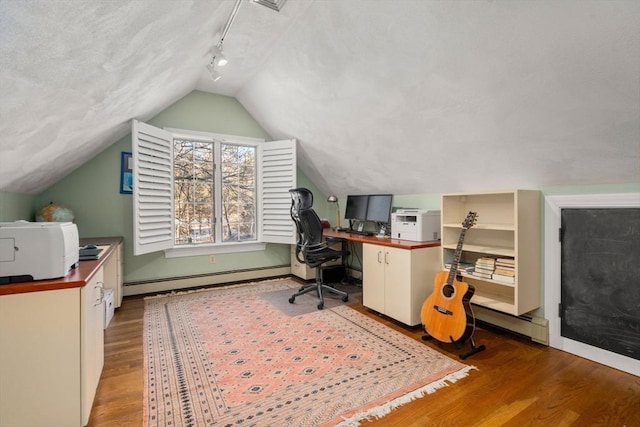 home office with a baseboard radiator, track lighting, vaulted ceiling, and light wood-type flooring