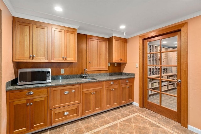 kitchen featuring dark stone countertops, sink, and crown molding