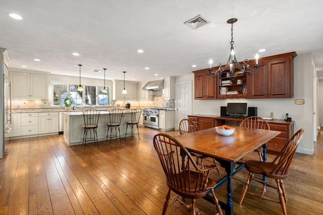 dining space with hardwood / wood-style flooring, sink, and an inviting chandelier