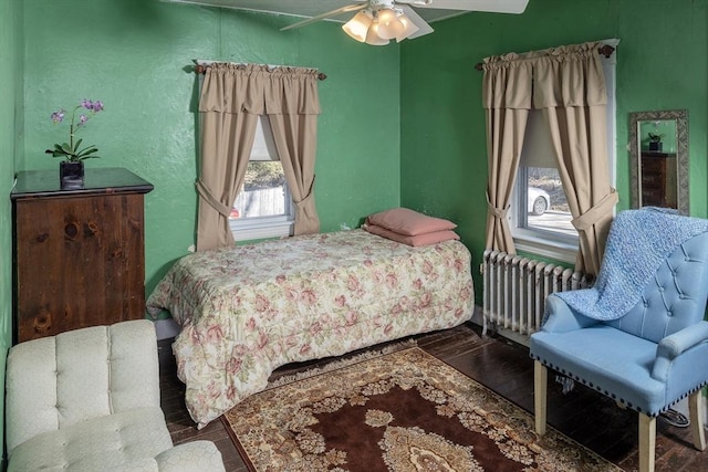 bedroom featuring a textured wall, radiator, a ceiling fan, and wood finished floors