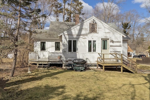 back of house featuring a deck, a chimney, a yard, and a shingled roof