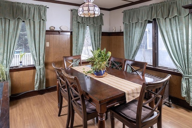 dining area with light wood-style floors and ornamental molding