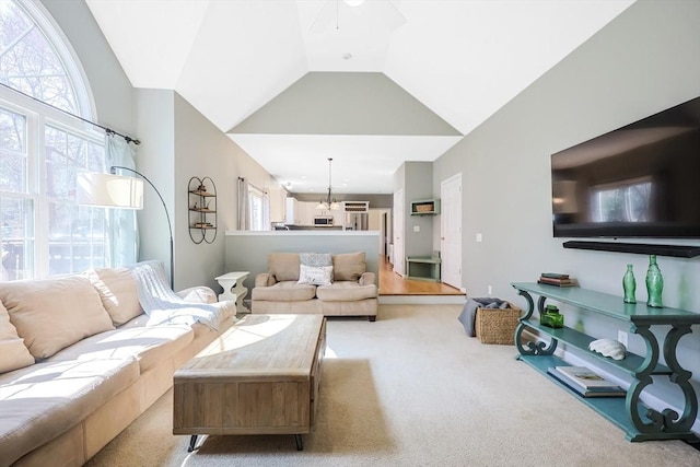 carpeted living room featuring ceiling fan with notable chandelier and lofted ceiling