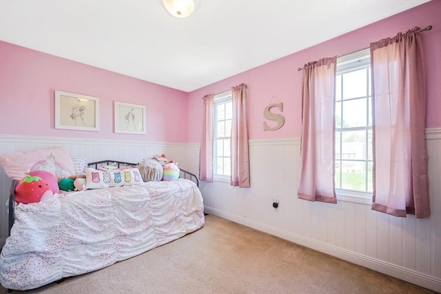 carpeted bedroom with a wainscoted wall
