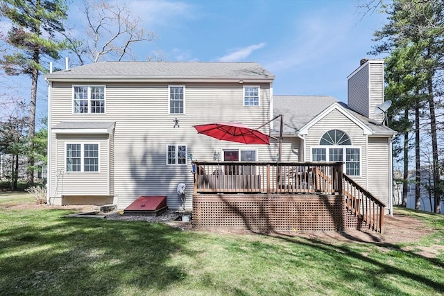back of property featuring a lawn, a chimney, and a deck