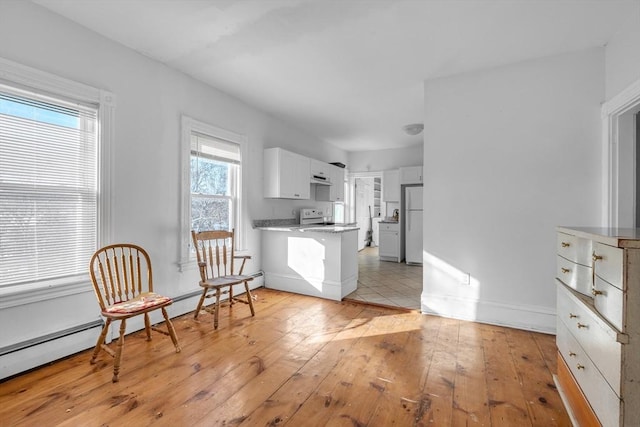 kitchen with white cabinetry, light wood-type flooring, and white appliances