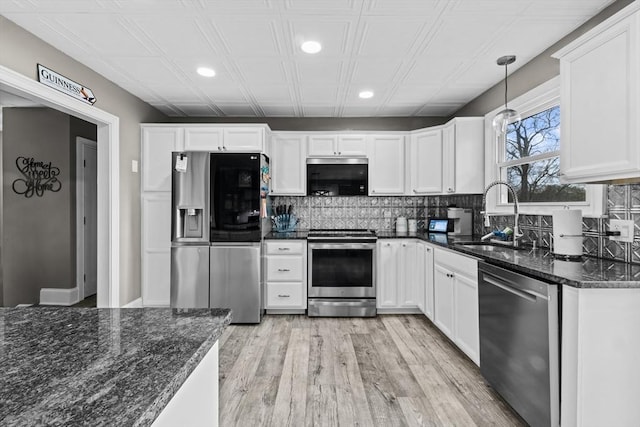 kitchen featuring white cabinetry, appliances with stainless steel finishes, decorative light fixtures, and sink