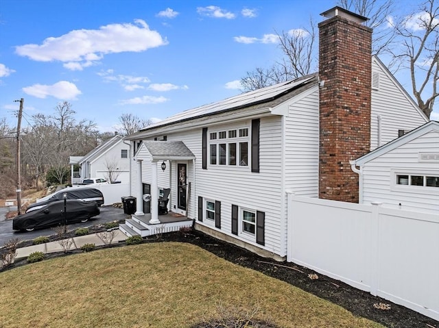 view of front of property featuring a front lawn and solar panels