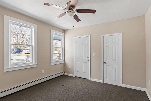 unfurnished bedroom with dark colored carpet, baseboards, baseboard heating, and ceiling fan