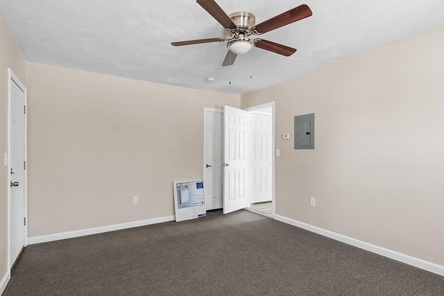 spare room featuring electric panel, a ceiling fan, baseboards, and dark carpet