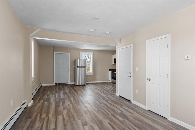 unfurnished living room featuring wood finished floors, baseboards, and baseboard heating