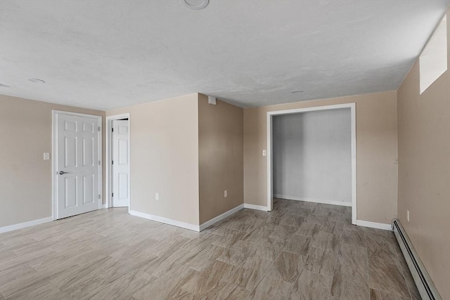 unfurnished room featuring baseboard heating and baseboards