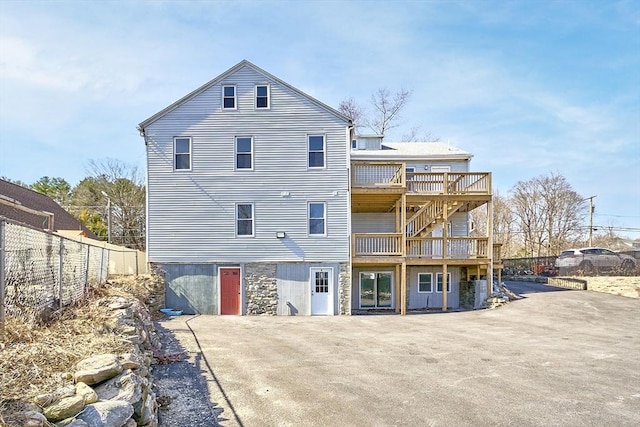 rear view of property featuring a deck and fence