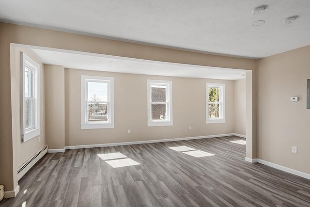 unfurnished room with wood finished floors, baseboards, and a baseboard radiator