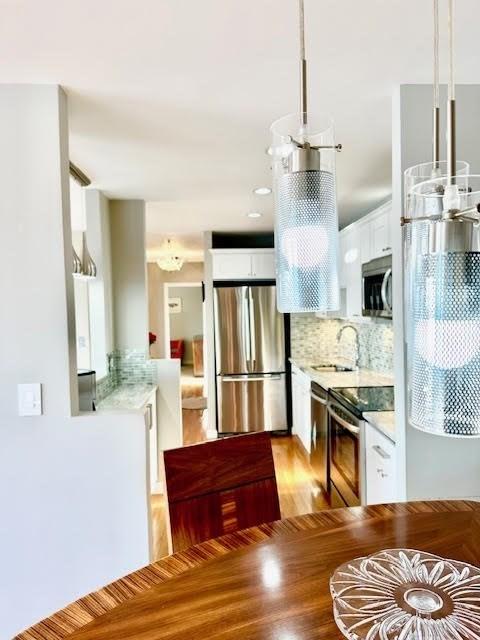 kitchen featuring white cabinetry, sink, tasteful backsplash, pendant lighting, and appliances with stainless steel finishes