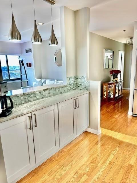 bar featuring white cabinets, backsplash, light hardwood / wood-style floors, and light stone countertops