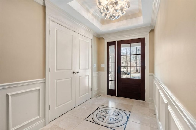 foyer featuring a wainscoted wall, a tray ceiling, and crown molding