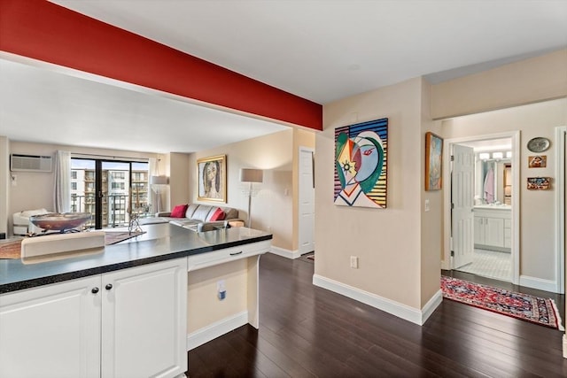 131 Coolidge Ave Unit 621, Watertown, MA 02472 - kitchen with dark countertops, open floor plan, dark wood-style flooring, white cabinetry, and an AC wall unit
