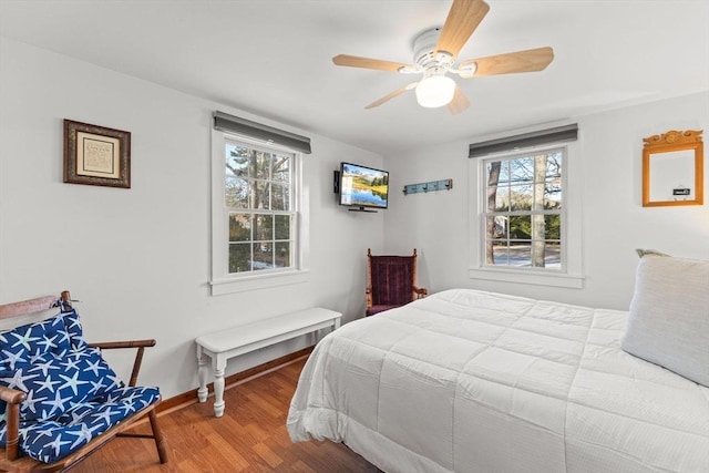 bedroom with hardwood / wood-style flooring, ceiling fan, and multiple windows