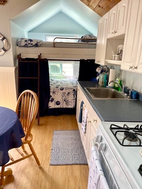 kitchen featuring white cabinets, light wood-type flooring, and white gas stove