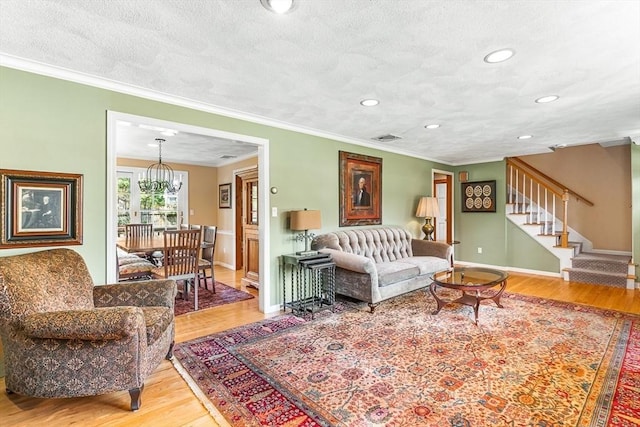 living room featuring stairway, baseboards, ornamental molding, and wood finished floors
