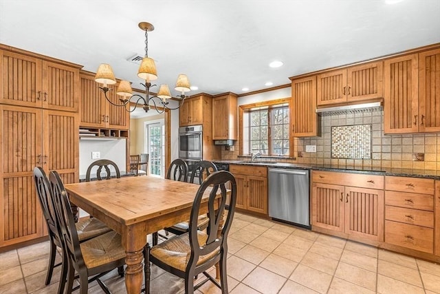 kitchen with appliances with stainless steel finishes, a healthy amount of sunlight, an inviting chandelier, and tasteful backsplash