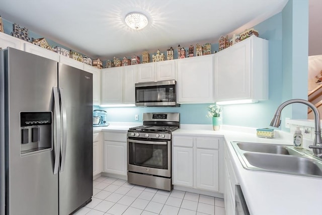 kitchen with light tile patterned floors, white cabinets, a sink, and appliances with stainless steel finishes