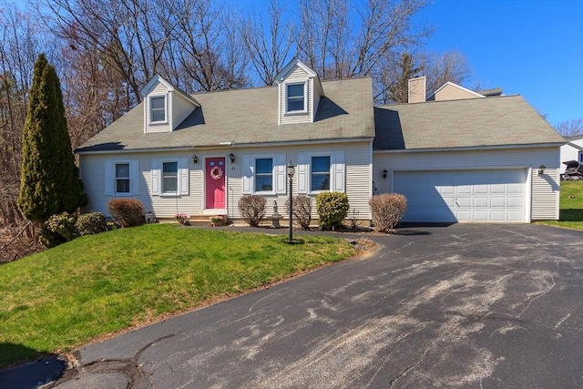 cape cod house with a chimney, a front lawn, driveway, and a garage