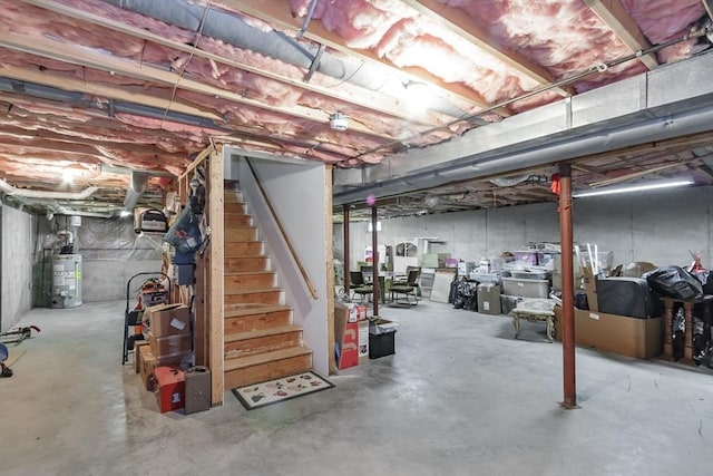 unfinished below grade area featuring water heater and stairway