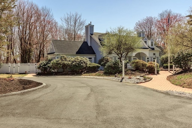 view of side of property featuring a shingled roof, a chimney, and fence