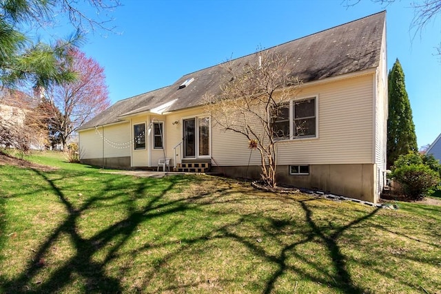 back of property with a lawn, entry steps, and roof with shingles