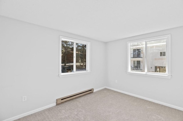 carpeted empty room with a baseboard radiator and plenty of natural light