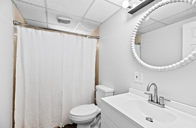 bathroom featuring toilet, a drop ceiling, curtained shower, and vanity