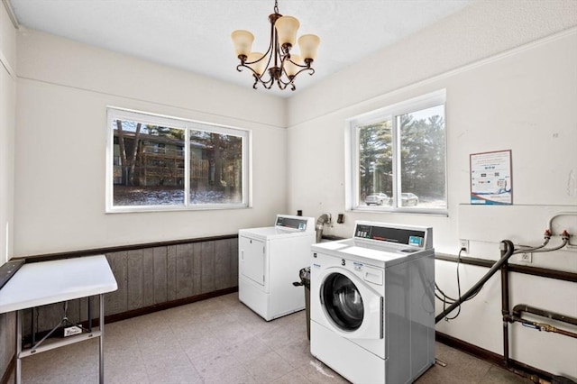 laundry room with washing machine and clothes dryer, a chandelier, and wood walls