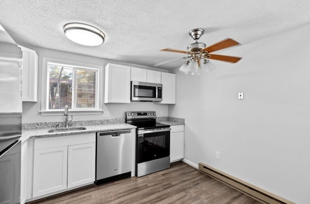 kitchen with stainless steel appliances, baseboard heating, white cabinetry, ceiling fan, and sink